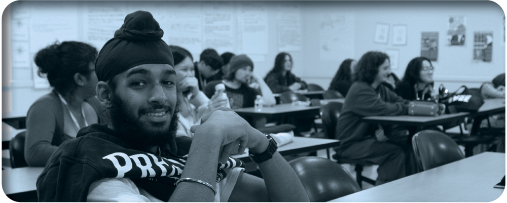 student sits at desk and smiles