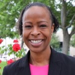 Headshot of Kaneesha Tarrant in a black jacket and fuschia shirt