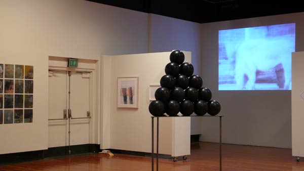 art installation featuring a pyramid of shiny black balls on a table
