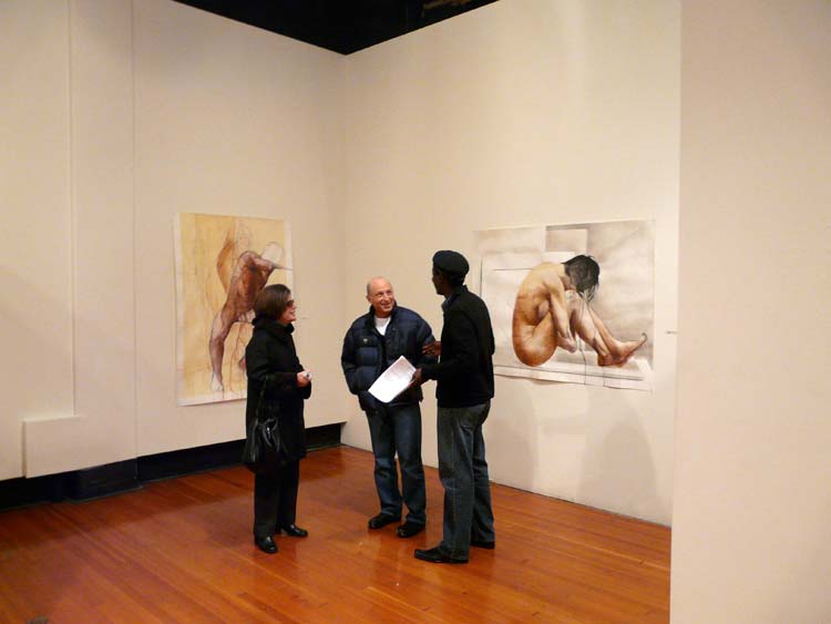 Gallery visitors stand in front of the drawings on the wall