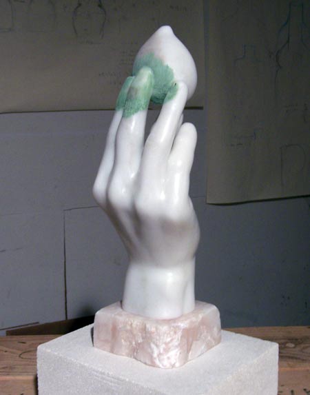 marble statue of a hand holding a fig by blue-green fingertips