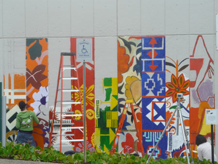 an artist paints one end of the mural, with more columns of art having appeared since the last shot