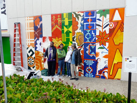 artists stand in front of the almost-completed mural