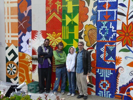 the artists pose in front of the almost-completed mural