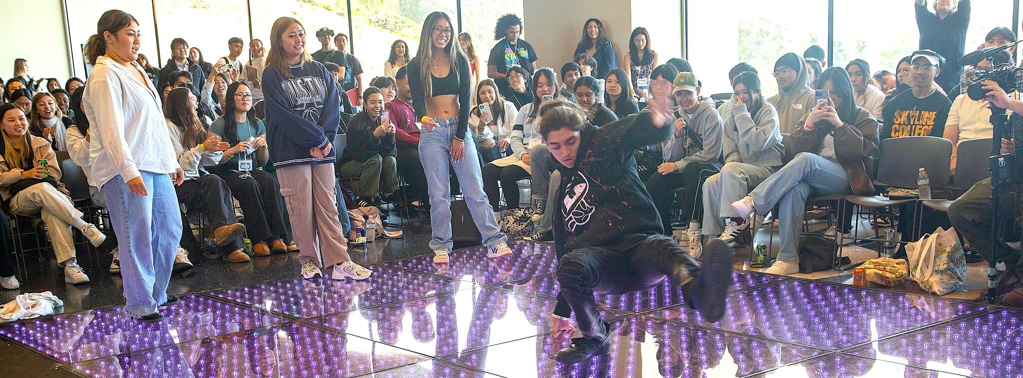 Rock the School Bells activity: dance battle on a lit-up purple floor in front of a crowd