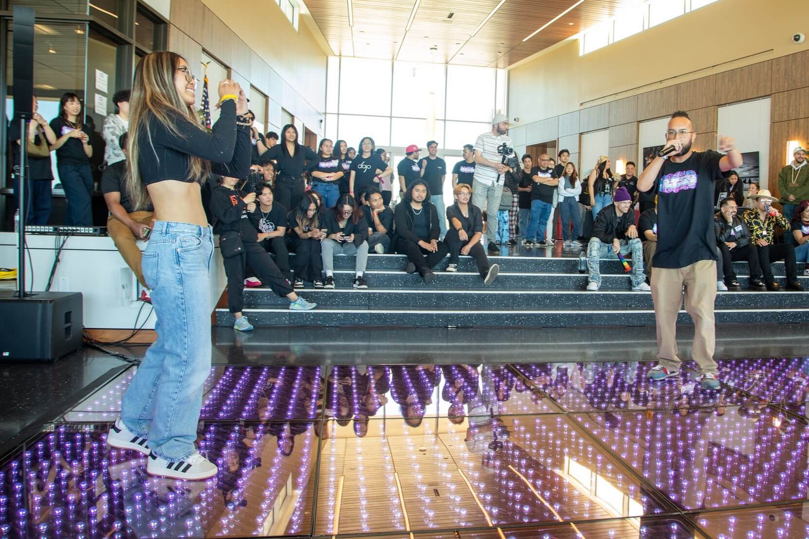 Rock the School Bells activity: dance battle on a lit-up purple floor in front of a crowd