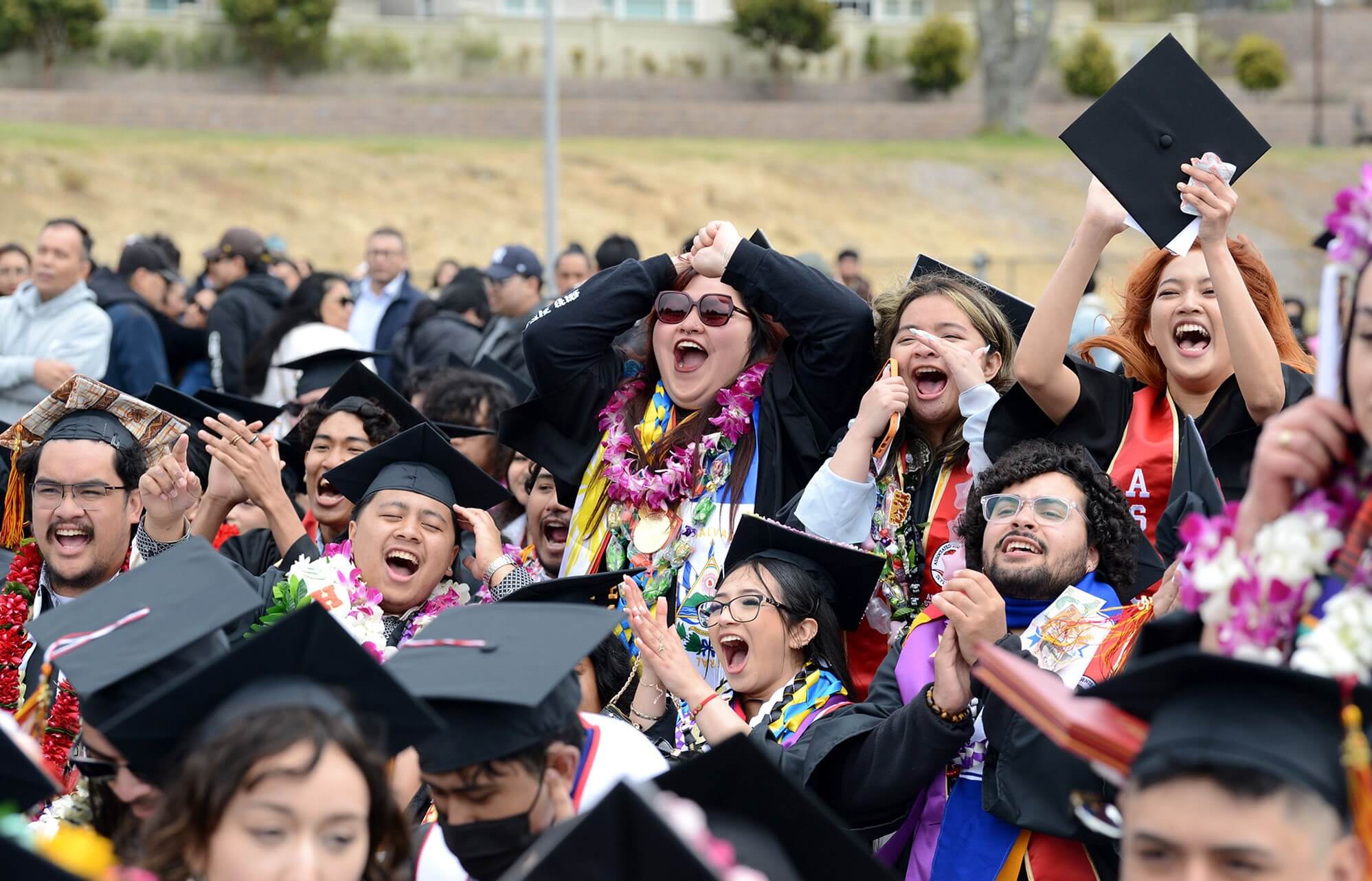 a crowd of graduates celebrates in the audience at Commencement