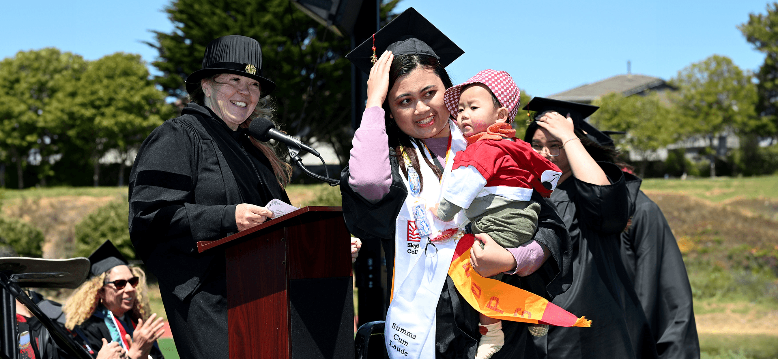 EOPS graduate holding her baby receives her degree at Skyline College Commencement