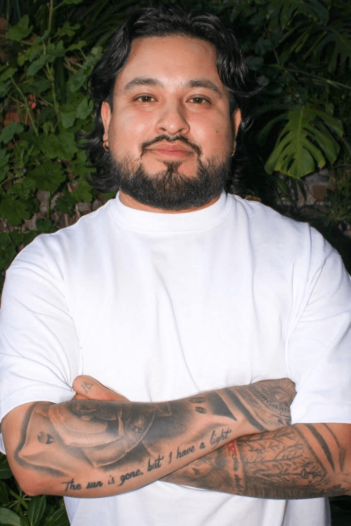 Headshot of Ronny Batista crossing his arms in a white t-shirt