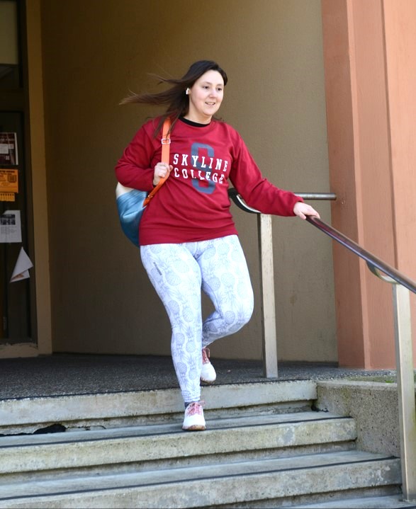 Skyline College student with backpack leaves a building down a flight of stairs