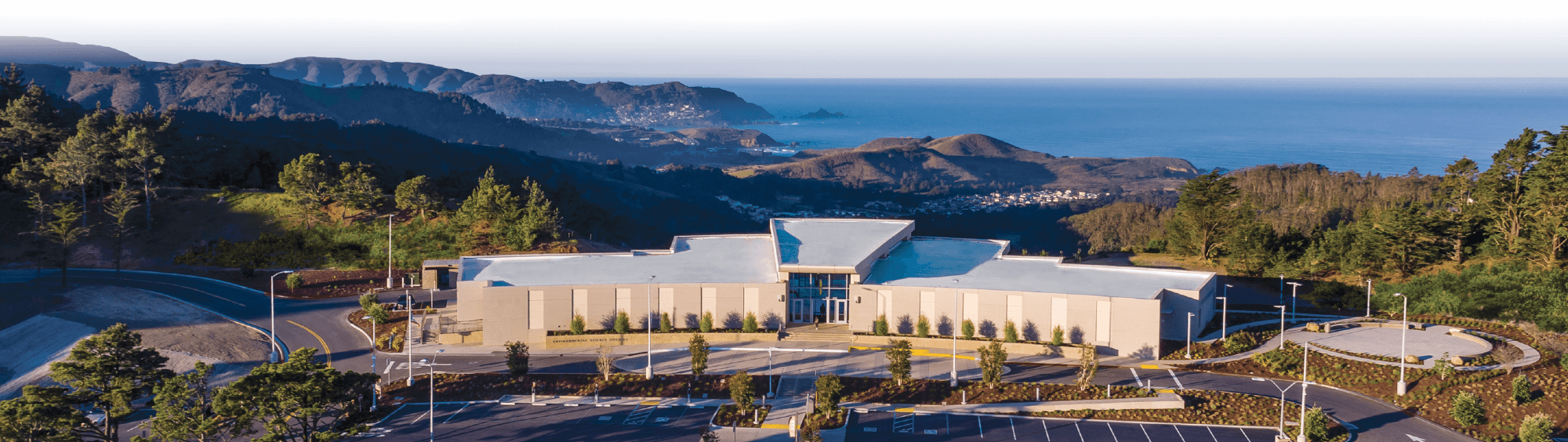 aerial view of campus by Building 12 on a clear day with blue ocean and green hills in the background
