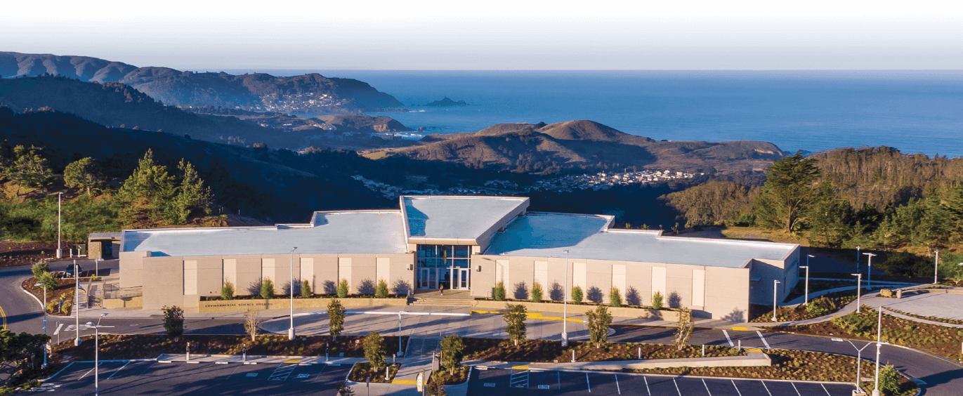 aerial view of campus by Building 12 on a clear day with blue ocean and green hills in the background