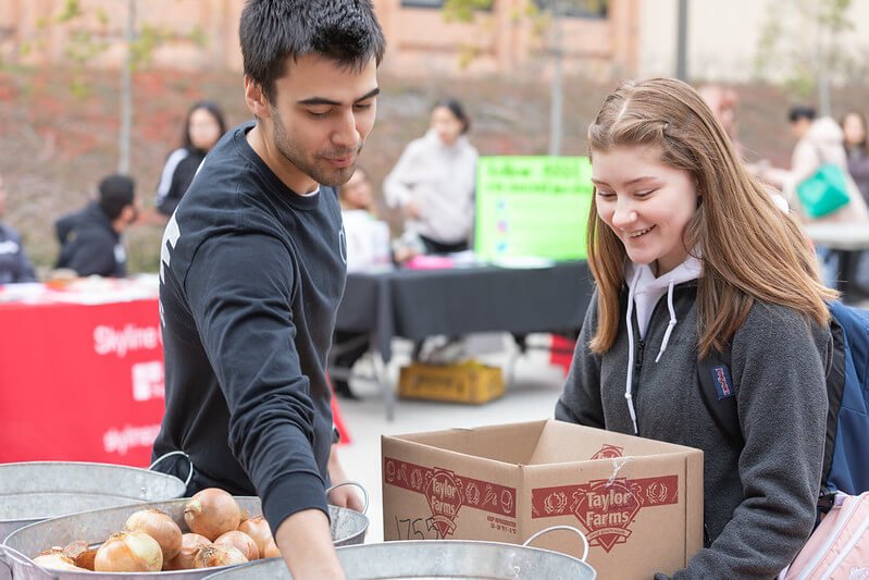Two Skyline College students with a box of food at the Free Community Market