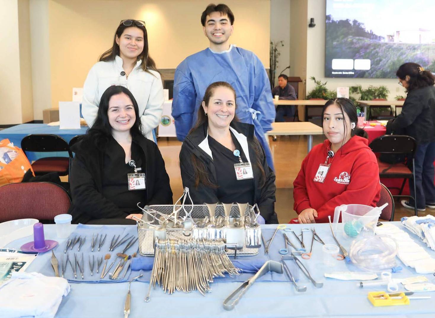a group of surgical technology students sit at a table displaying their tools