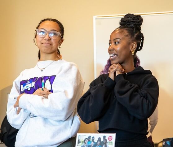 Two Umoja students stand at a table together