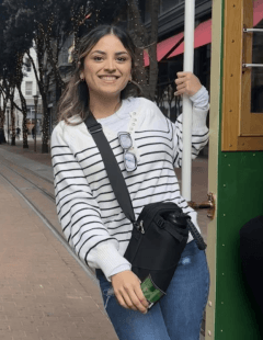 Mia Villalobos smiles while leaning on a cable car handrail in San Francisco